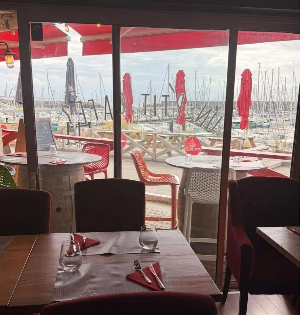 La salle du Skipper, tables dressées devant les baies vitrées ouvertes sur le port